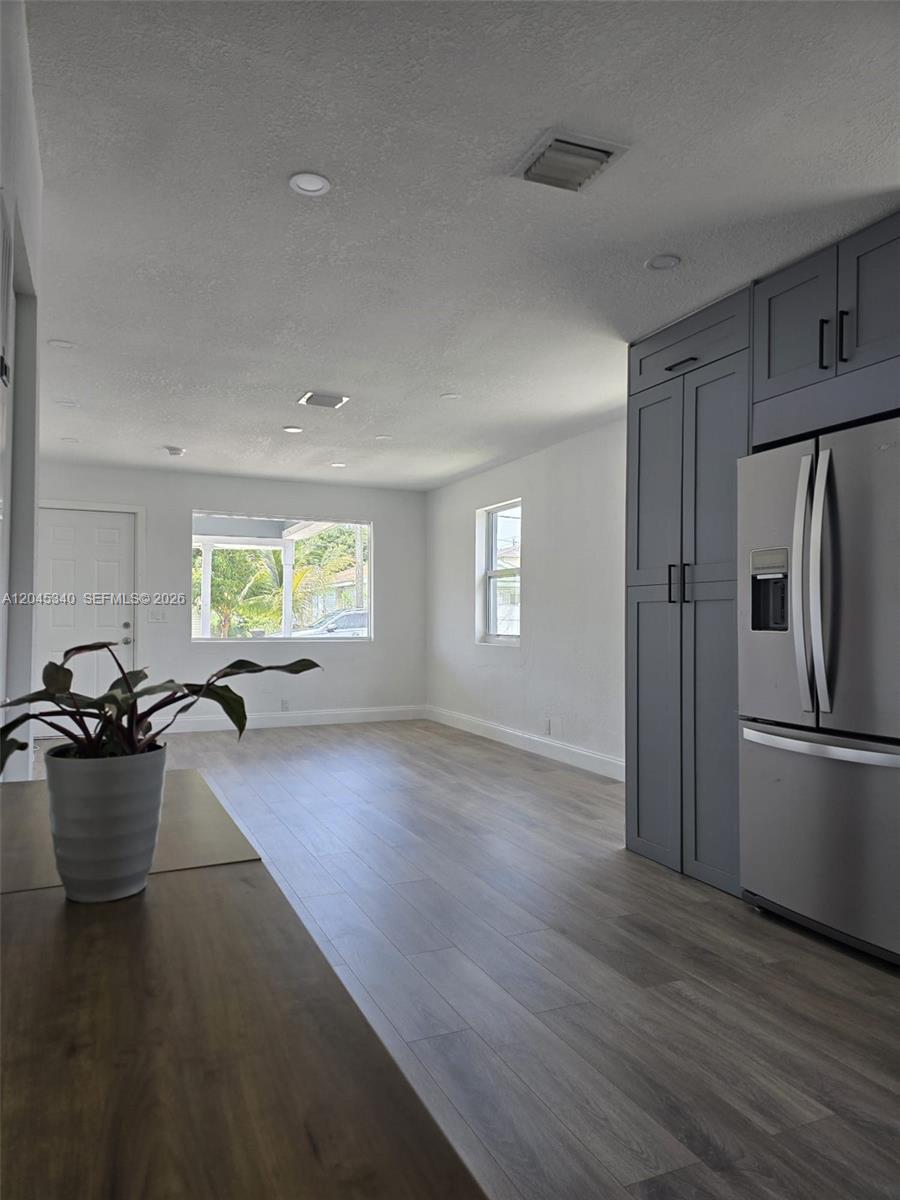 A kitchen with gray cabinetry and stainless steel appliances opens into a bright living area — 719 21st St, West Palm Beach FL 33407, WEST PALM BEACH, FL