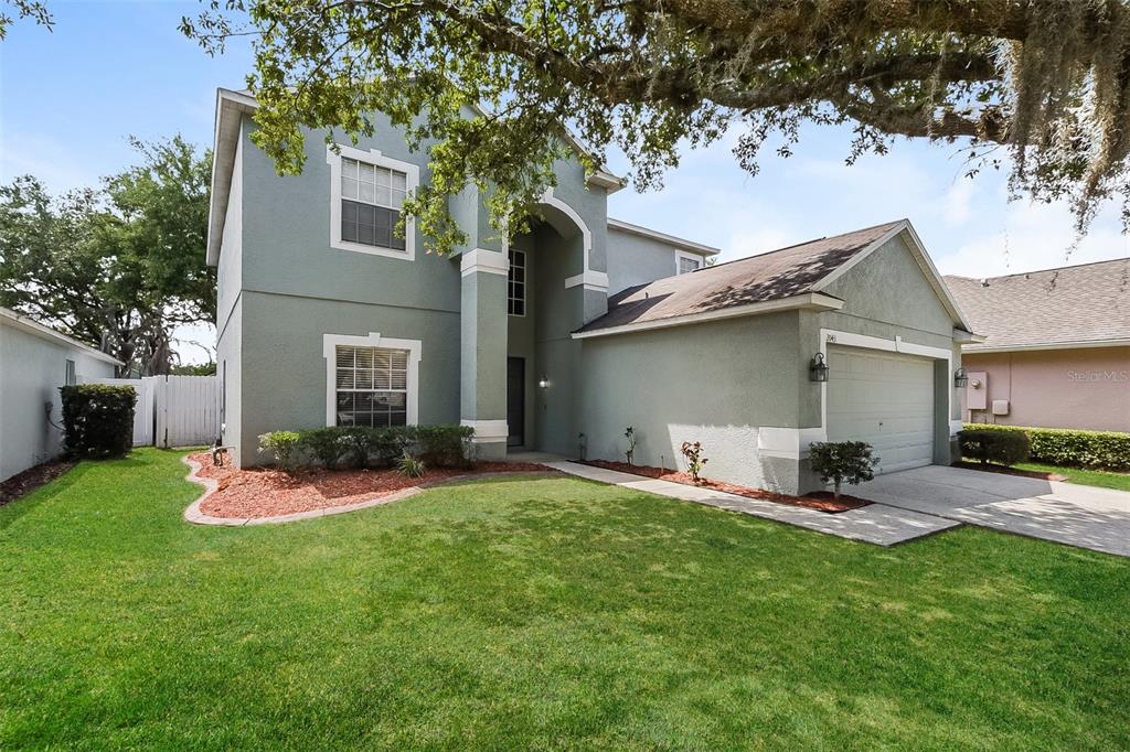 A two-story house with a light green stucco exterior, a garage, and a front lawn — 2043 HAMMOCK MOSS DRIVE, ORLANDO, FL