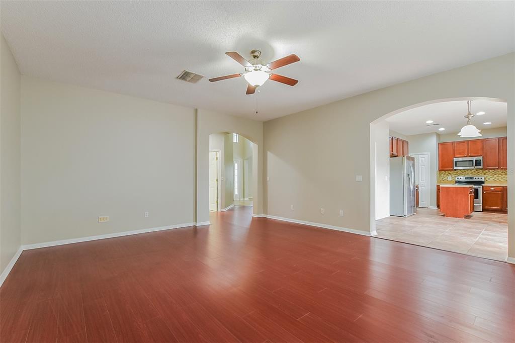 A spacious living room with wood-look flooring leads to an arched entryway into the kitchen — 2043 HAMMOCK MOSS DRIVE, ORLANDO, FL