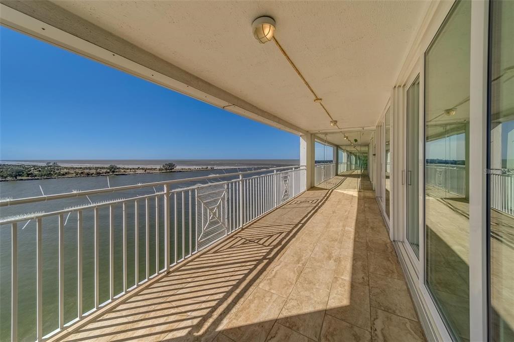 A long, tiled balcony with a white metal railing overlooks a body of water — 675 S GULFVIEW BOULEVARD UNIT PH1, CLEARWATER BEACH, FL