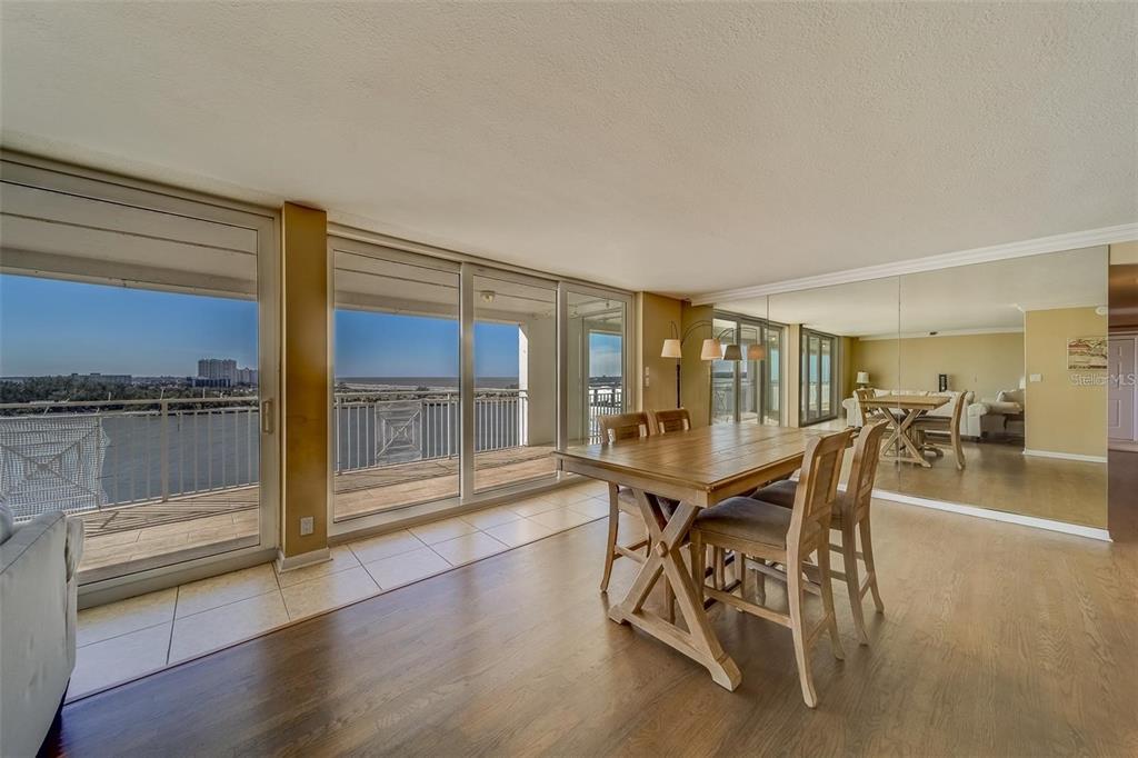 A dining area with a wooden table, tile flooring, and sliding glass doors overlooking the water — 675 S GULFVIEW BOULEVARD UNIT PH1, CLEARWATER BEACH, FL