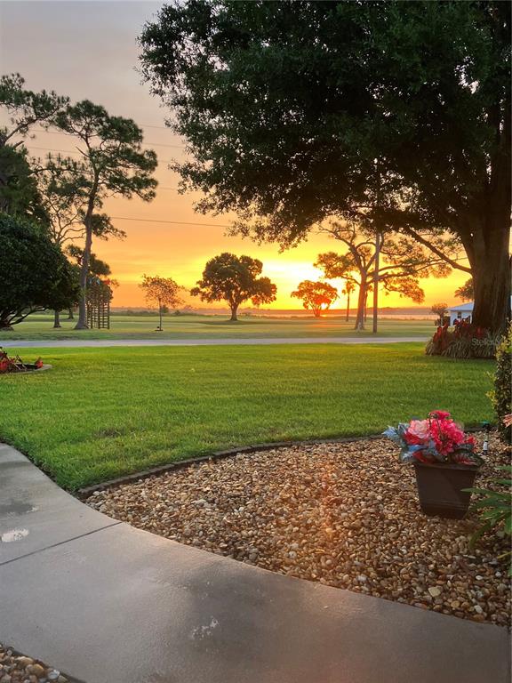 A view of a sunset over a grassy lawn with trees and a potted plant — 77 W LAKE DAMON DRIVE, AVON PARK, FL