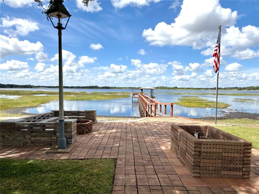 A brick patio features a fire pit, a lamp post, and a dock extending into water — 77 W LAKE DAMON DRIVE, AVON PARK, FL