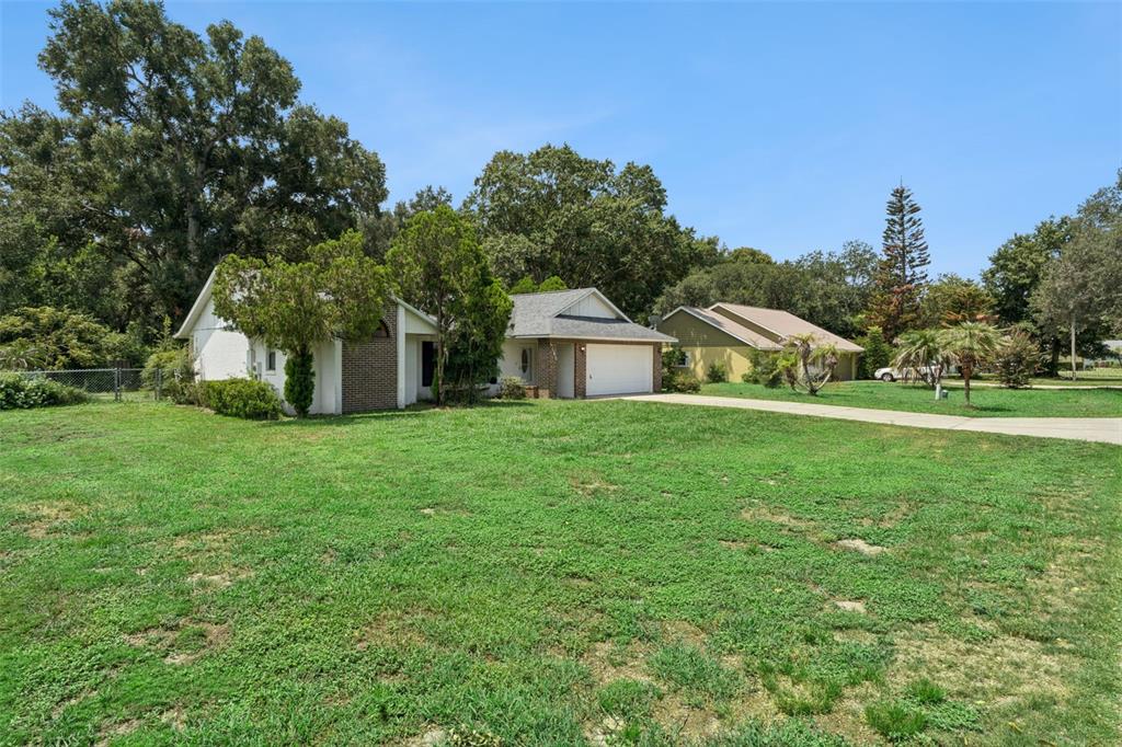 A single-story house with a white garage and brick accents sits on a grassy lot — 4160 WOOD DRIVE, MOUNT DORA, FL