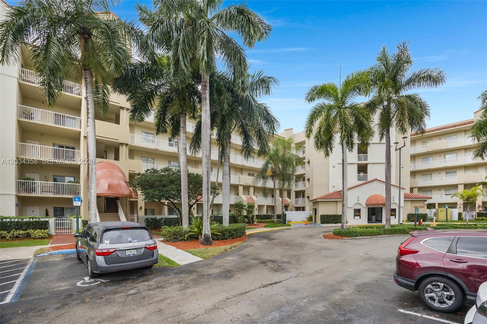 A multi-story apartment complex features palm trees, balconies, and a paved parking lot — 10720 NW 66th St # 202, Doral FL 33178, DORAL, FL