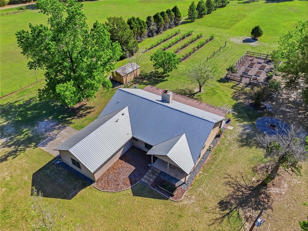 An aerial view shows a house with a metal roof, garden beds, and a shed — 15223 NW STATE ROAD 45, HIGH SPRINGS, FL