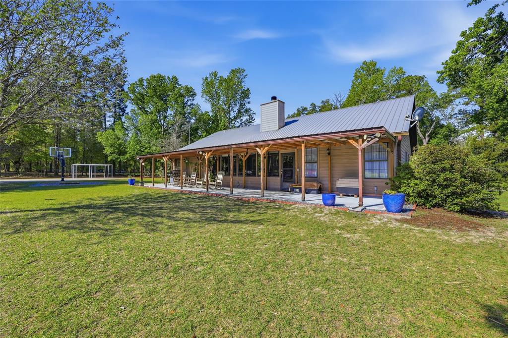 A single-story house with a metal roof and a long covered porch faces a lawn — 15223 NW STATE ROAD 45, HIGH SPRINGS, FL