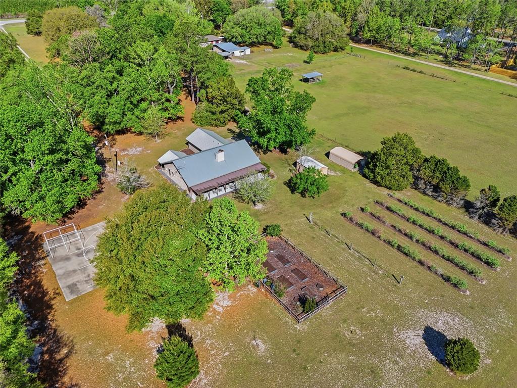 An aerial view shows a house with a metal roof, a garden, and a basketball court — 15223 NW STATE ROAD 45, HIGH SPRINGS, FL
