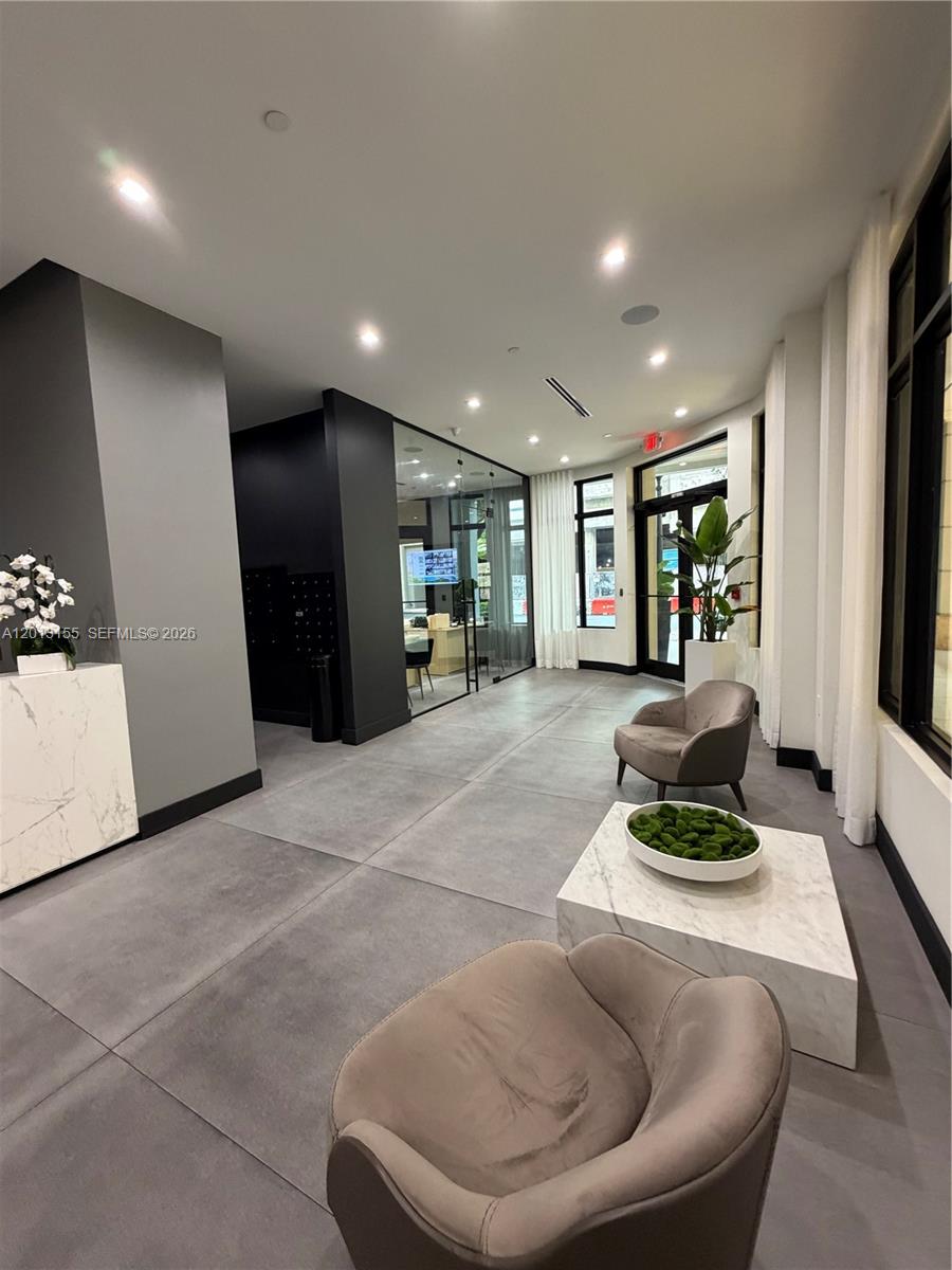 A living room with a grey sofa, coffee table, and an open kitchen with bar stools — 4100 Salzedo St # 508, Coral Gables FL 33146, CORAL GABLES, FL