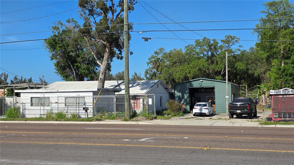 A white house and a green metal workshop sit behind a chain-link fence — 2319 S 50TH STREET, TAMPA, FL
