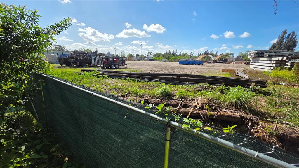 A fenced, dirt-covered construction or industrial lot with stacked materials and trailers under a sky — 2319 S 50TH STREET, TAMPA, FL