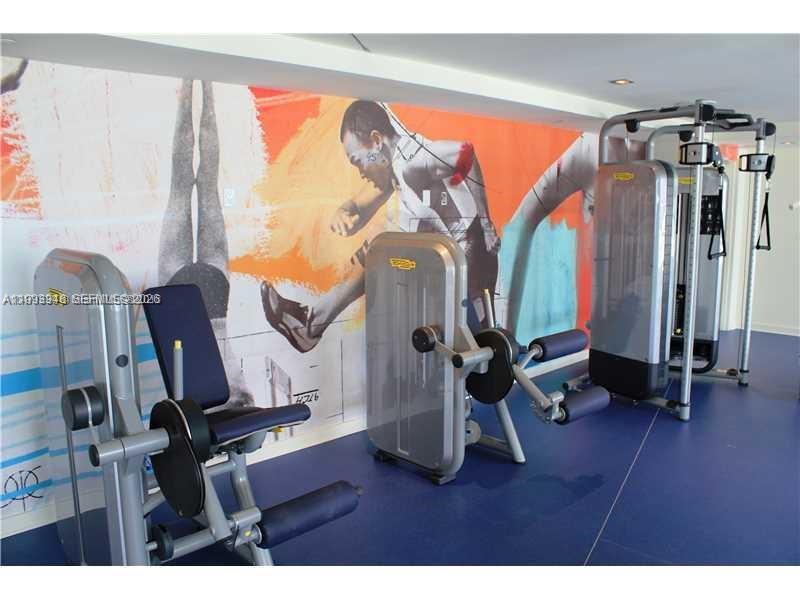 A gym room features three Technogym exercise machines against a large, colorful athletic-themed wall mural — 4250 Biscayne Blvd # 815, Miami FL 33137, MIAMI, FL