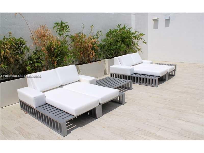 Two modern outdoor lounge chairs with white cushions sit on a tiled patio near bamboo — 4250 Biscayne Blvd # 815, Miami FL 33137, MIAMI, FL