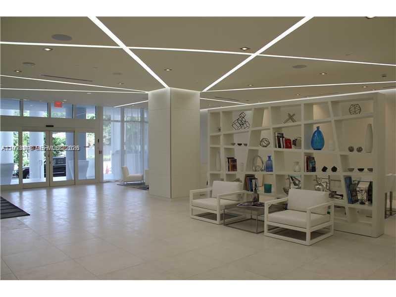 A modern lobby features white tile floors, geometric ceiling lighting, and a white open-shelf partition — 4250 Biscayne Blvd # 815, Miami FL 33137, MIAMI, FL