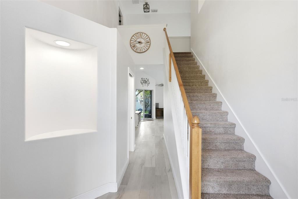 A carpeted staircase with a wooden railing leads up beside a white hallway — 609 RHODES DRIVE, DELAND, FL