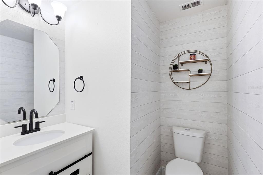 A bathroom features a white vanity, a round wall shelf, and white shiplap walls — 609 RHODES DRIVE, DELAND, FL