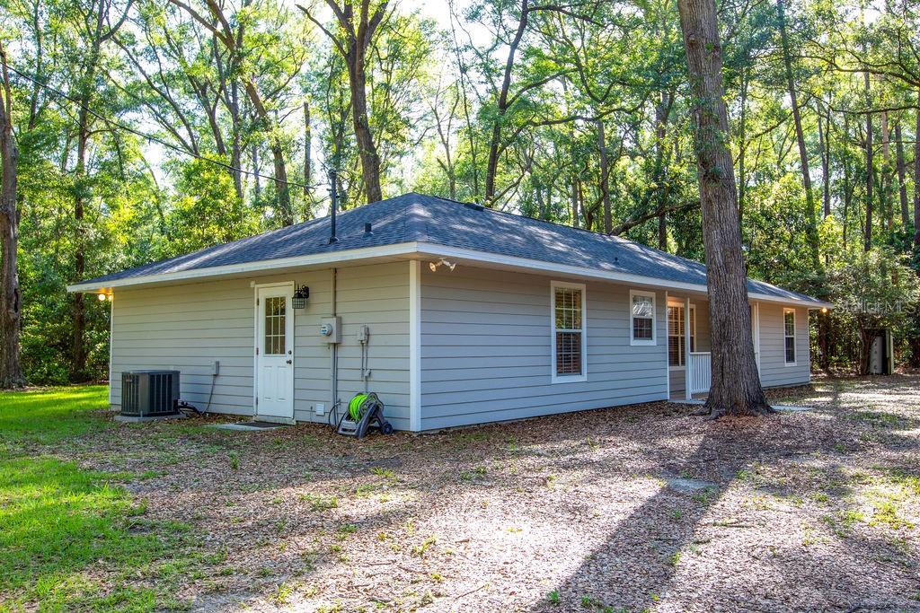 A light gray, single-story house with a hip roof sits in a wooded yard — 15713 NW 268TH TERRACE, HIGH SPRINGS, FL