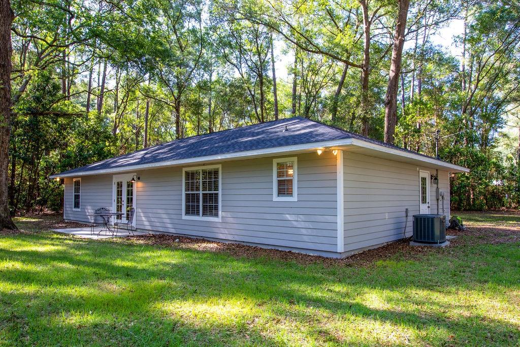 The exterior of a gray, single-story house with a dark roof sits in a wooded yard — 15713 NW 268TH TERRACE, HIGH SPRINGS, FL
