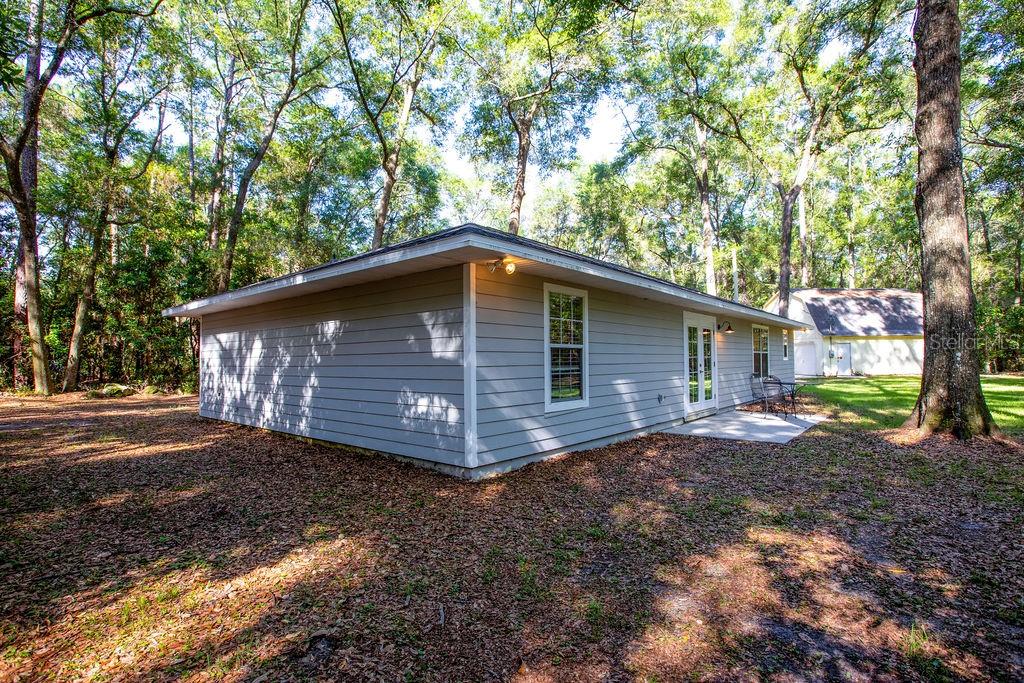 A gray, single-story house with horizontal siding sits in a wooded yard — 15713 NW 268TH TERRACE, HIGH SPRINGS, FL