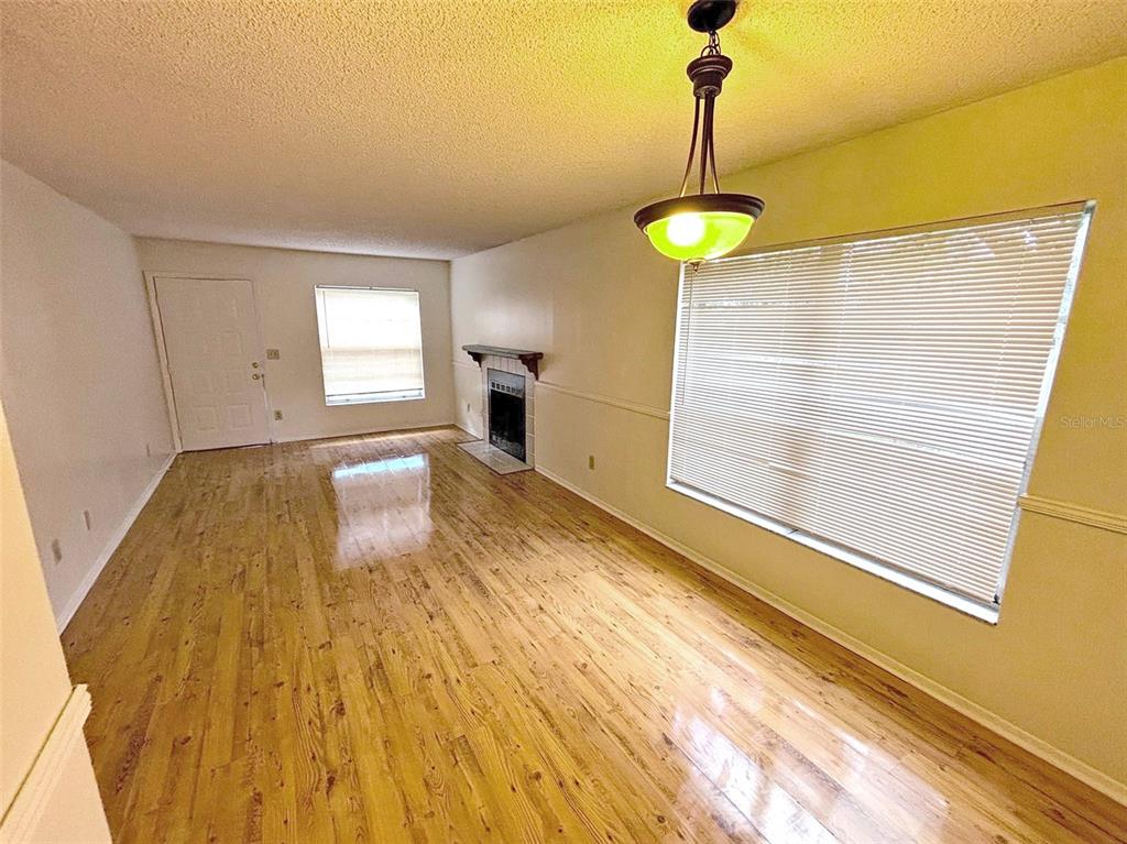A living room features light wood flooring, a fireplace, and a hanging pendant light — 4034 DREAM OAK PLACE UNIT 104, TAMPA, FL