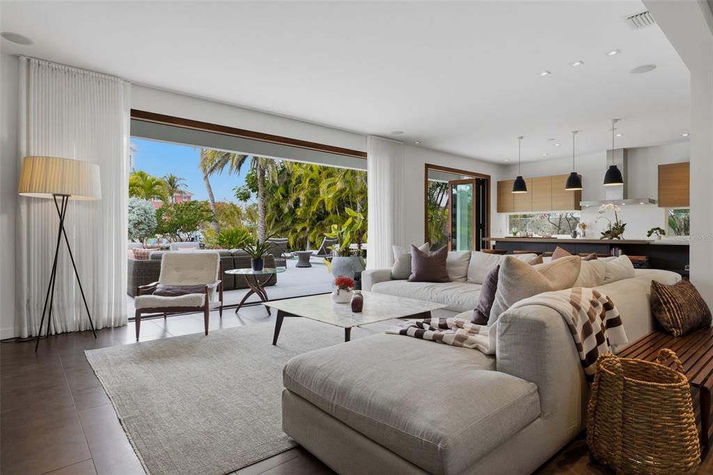 A bright living room with a large sectional sofa opens to a patio with palm trees — 541 S WASHINGTON DRIVE, SARASOTA, FL