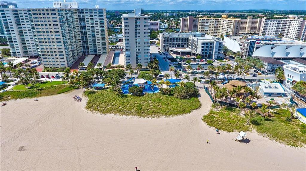 An aerial view shows a sandy beach, a playground, and several large residential buildings — 133 N Pompano Beach Boulevard # 108, Pompano Beach FL 33062, POMPANO BEACH, FL