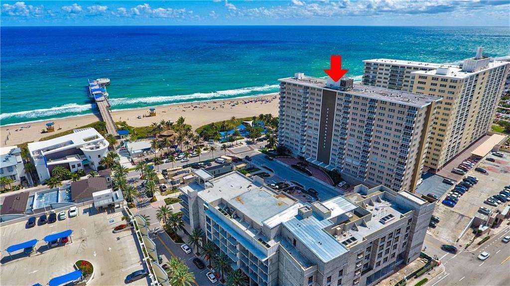 An aerial view shows a tall beachfront apartment building with a red arrow pointing upward — 133 N Pompano Beach Boulevard # 108, Pompano Beach FL 33062, POMPANO BEACH, FL