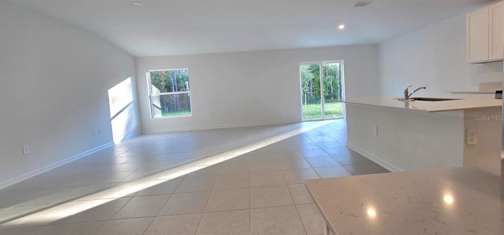 An open-concept living area features light-colored tile flooring, white walls, and a kitchen island — 5034 BARNET DRIVE, DAVENPORT, FL