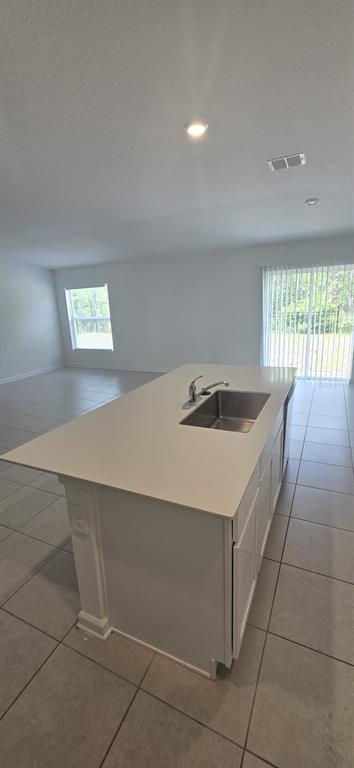 A kitchen island with a stainless steel sink sits on a tiled floor in a room — 5034 BARNET DRIVE, DAVENPORT, FL