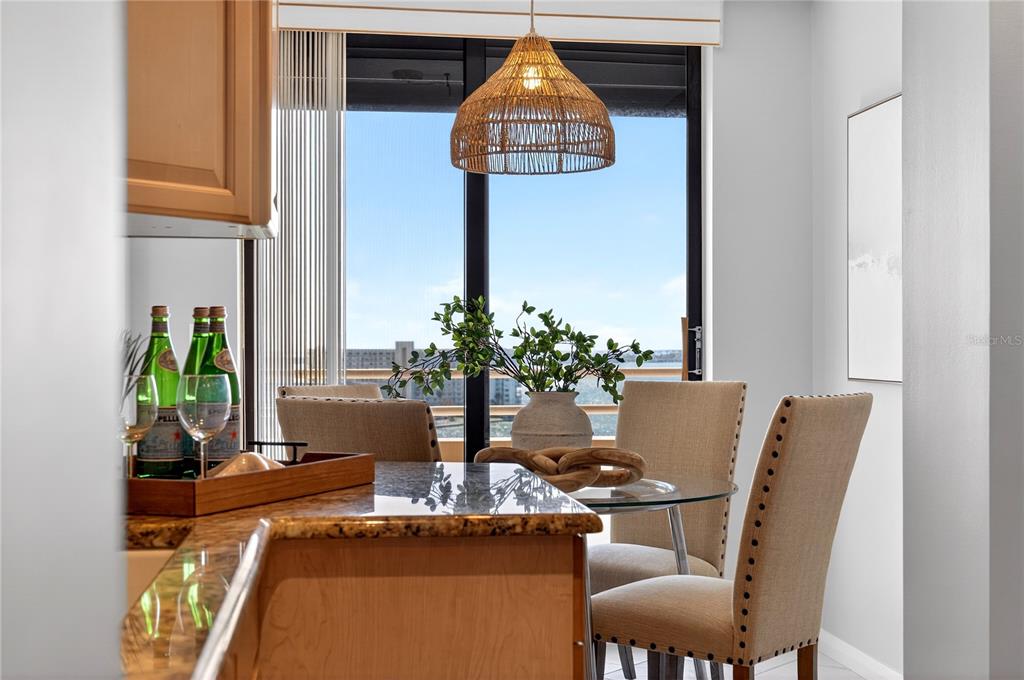 A dining area features a glass table, upholstered chairs, and a view of the water — 5950 PELICAN BAY PLAZA S UNIT 2E, GULFPORT, FL