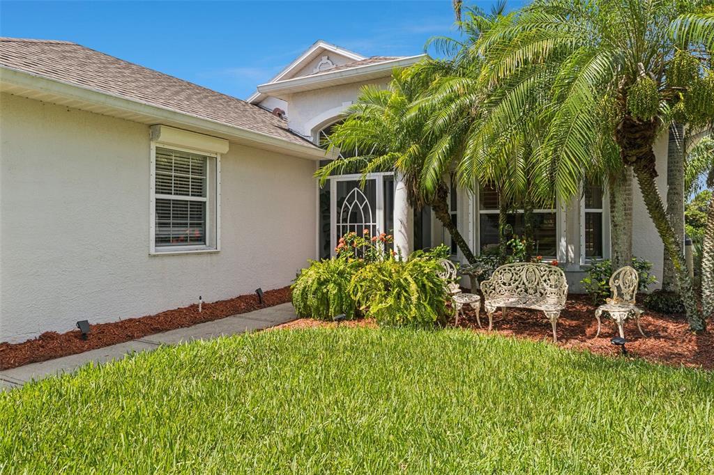 A white house exterior features a front entrance with a screen door and palm trees — 4680 PORTAGE TRAIL, MELBOURNE, FL