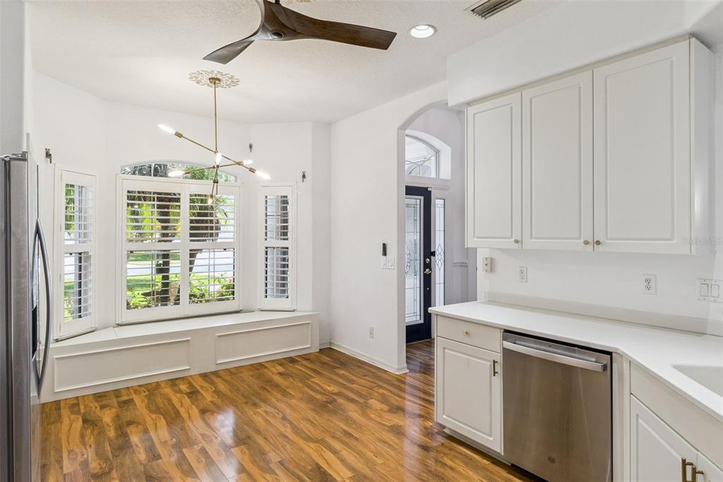 A kitchen area features white cabinets, stainless steel appliances, wood flooring, and a window seat — 4680 PORTAGE TRAIL, MELBOURNE, FL