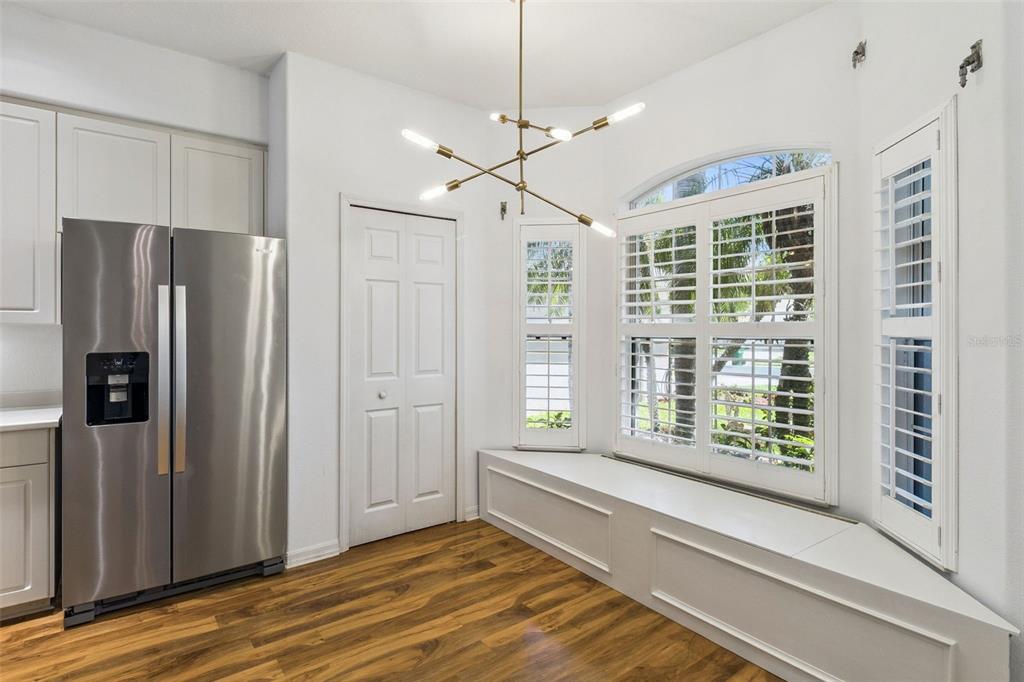 A kitchen breakfast nook features a built-in window bench, modern chandelier, and stainless steel refrigerator — 4680 PORTAGE TRAIL, MELBOURNE, FL