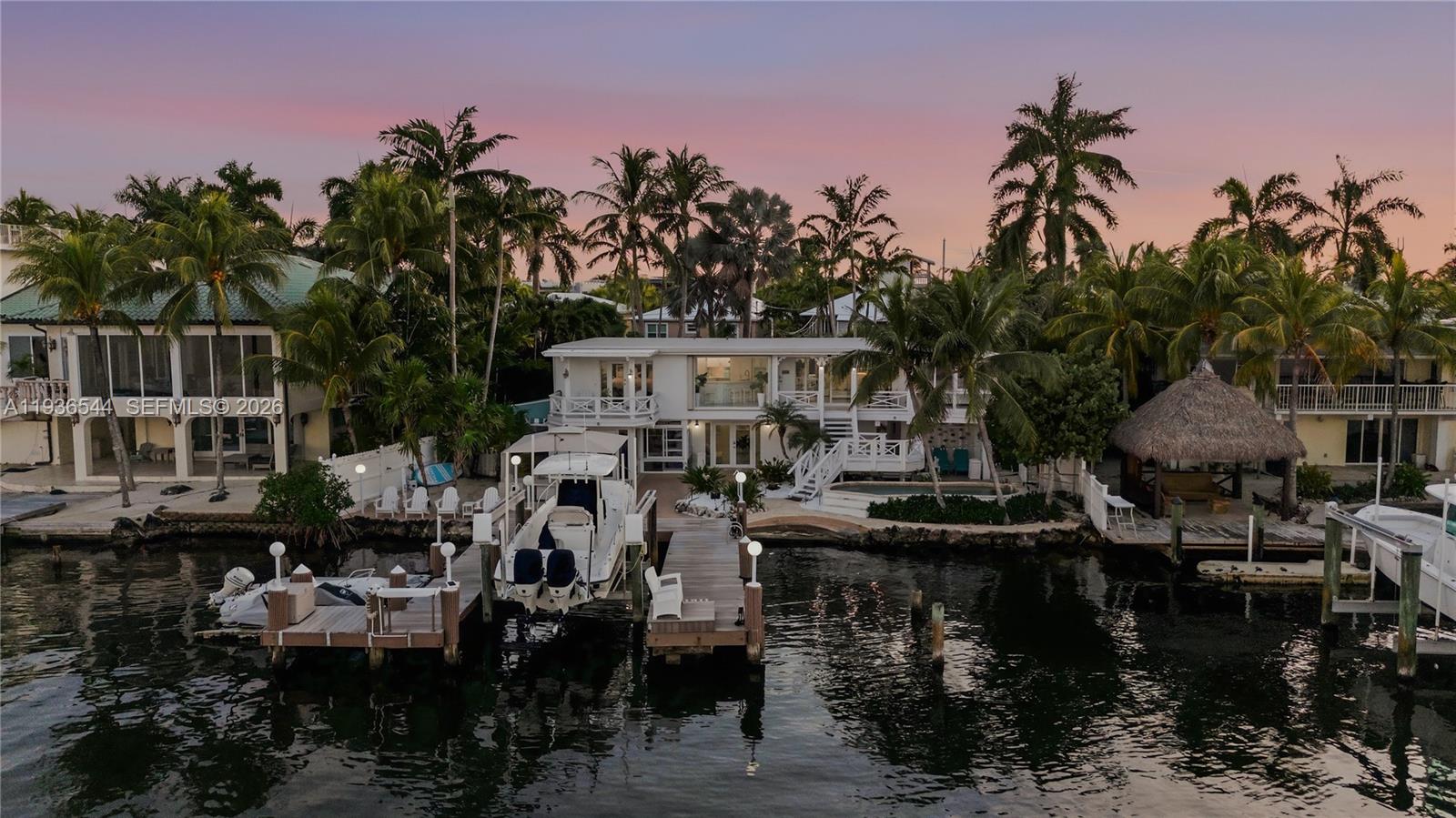 An aerial view of a waterfront home with a boat dock and palm trees — 16 North Dr, Key Largo FL 33037, KEY LARGO, FL