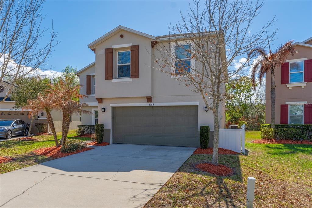 A two-story suburban house with a beige stucco exterior, brown shutters, and a two-car garage — 4752 BLUE DIAMOND STREET, KISSIMMEE, FL