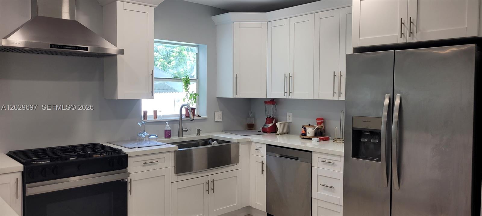 A modern kitchen features white cabinets, stainless steel appliances, and a large quartz-topped island — 701 NE 14th St, Homestead FL 33030, HOMESTEAD, FL