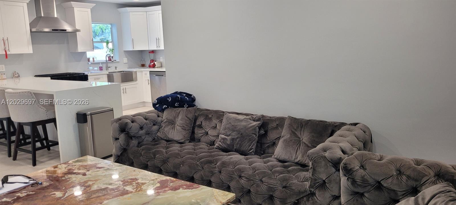 A living room features a tufted gray sofa, a marble coffee table, and a front door — 701 NE 14th St, Homestead FL 33030, HOMESTEAD, FL
