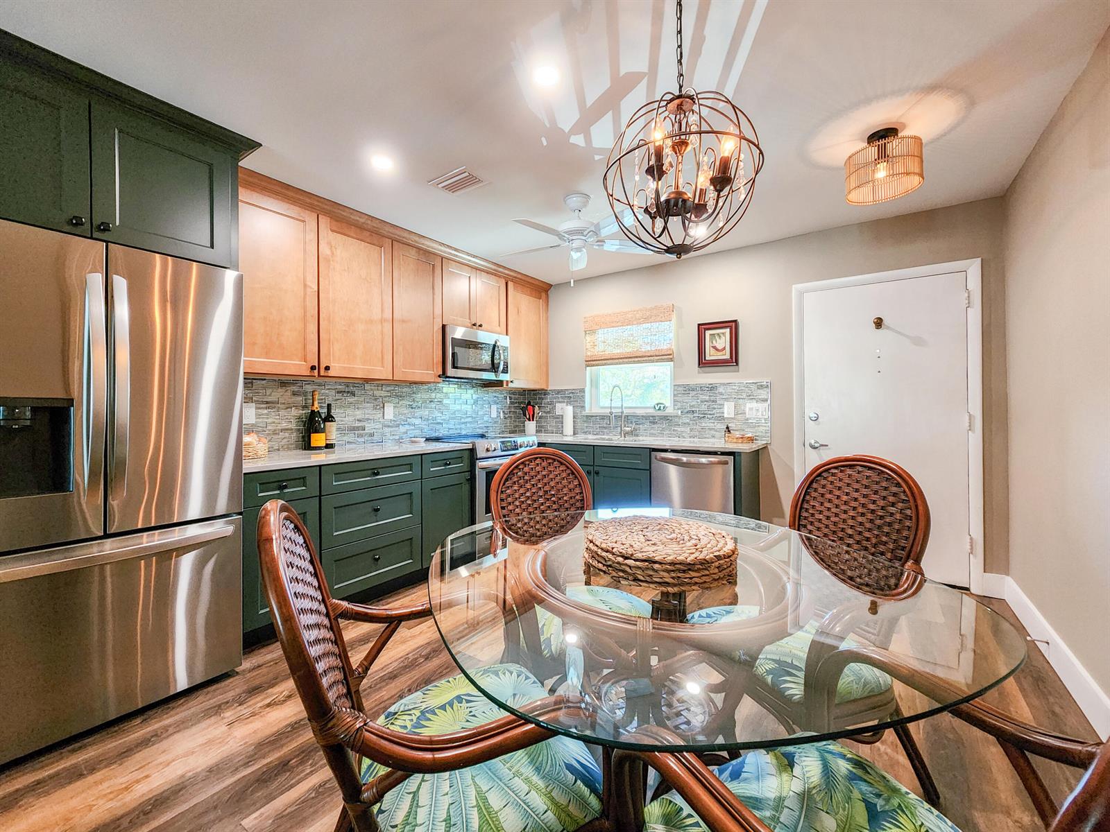 A kitchen features green lower cabinets, wood upper cabinets, stainless steel appliances, and a dining set — 2800 Indian River Boulevard # 8, Vero Beach FL 32960, VERO BEACH, FL
