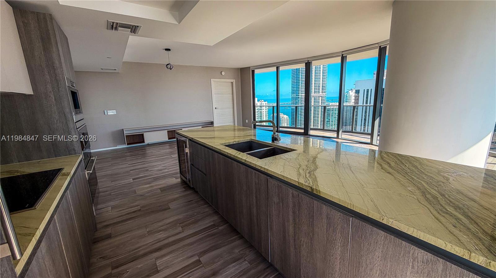 A modern kitchen features a large stone island, dark wood cabinetry, and floor-to-ceiling windows — 801 S Miami Ave # 4501, Miami FL 33130, MIAMI, FL