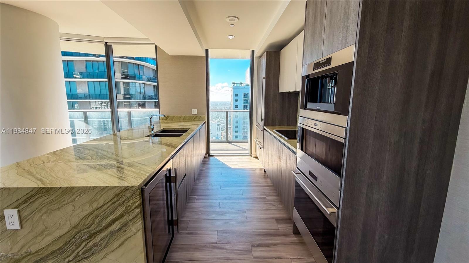 A modern kitchen features stone countertops, dark wood cabinetry, stainless steel appliances, and floor-to-ceiling windows — 801 S Miami Ave # 4501, Miami FL 33130, MIAMI, FL