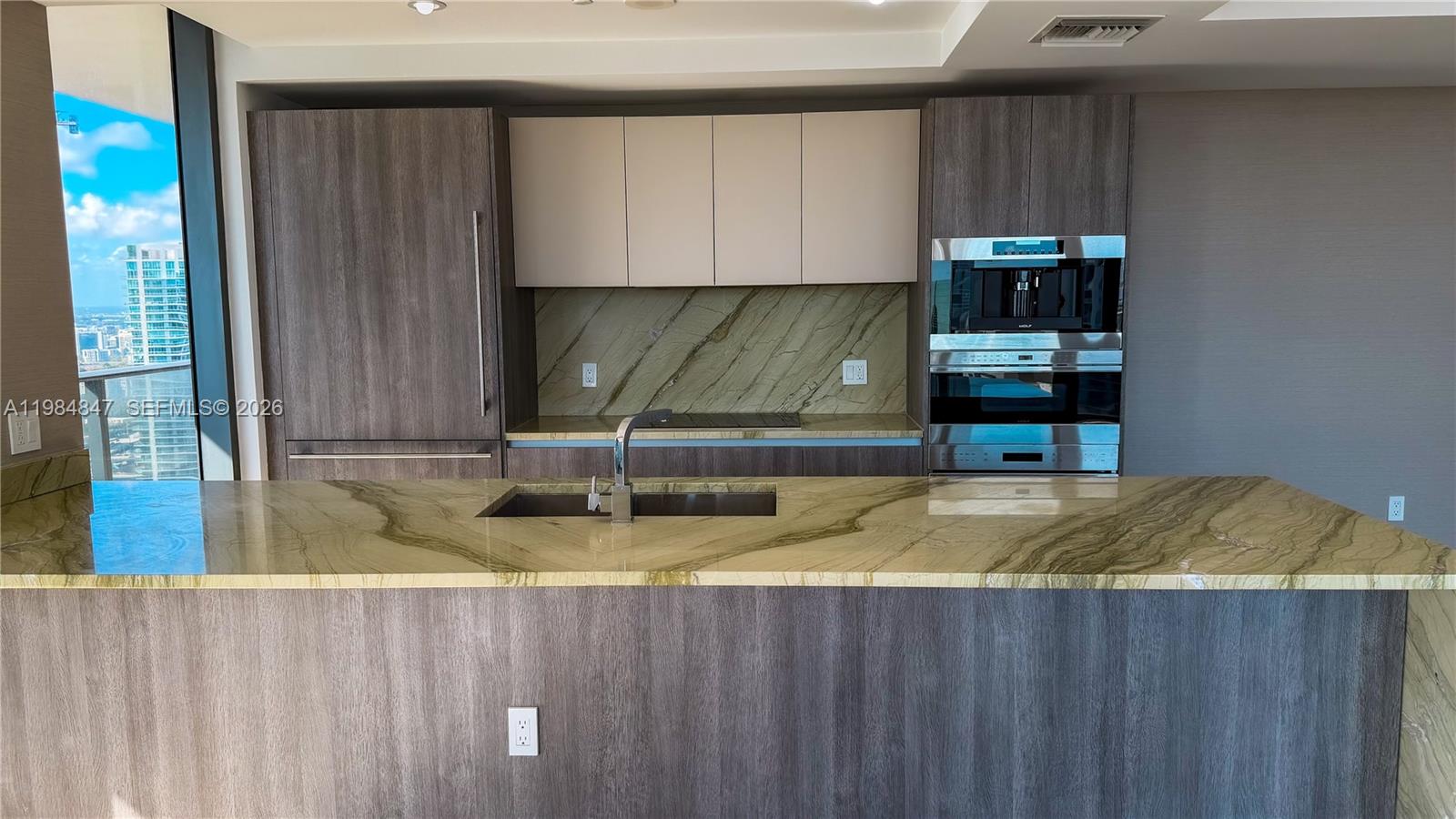 A modern kitchen features a stone island, dark wood cabinetry, and stainless steel built-in appliances — 801 S Miami Ave # 4501, Miami FL 33130, MIAMI, FL