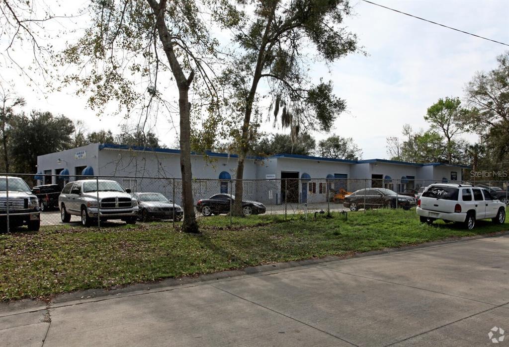 A single-story commercial building with multiple garage bays sits behind a chain-link fence — 5508 BENCHMARK LANE UNIT 112, SANFORD, FL