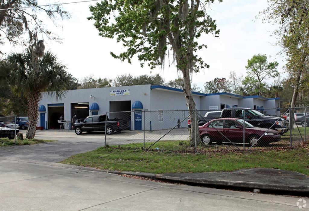 An exterior view of a single-story auto repair shop with multiple garage bays and vehicles — 5508 BENCHMARK LANE UNIT 112, SANFORD, FL
