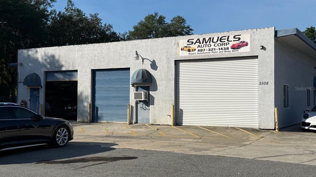 The exterior of a commercial automotive repair shop features three roll-up doors and stucco walls — 5508 BENCHMARK LANE UNIT 112, SANFORD, FL