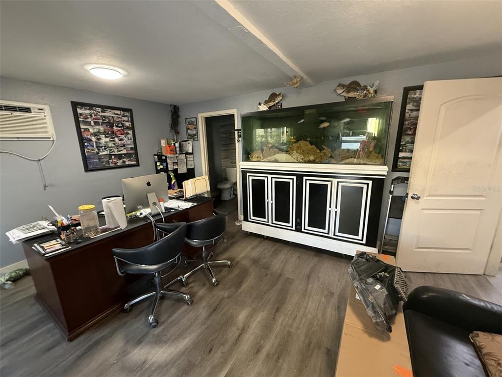A home office features a large fish tank, a dark wood desk, and wood-look flooring — 5508 BENCHMARK LANE UNIT 112, SANFORD, FL