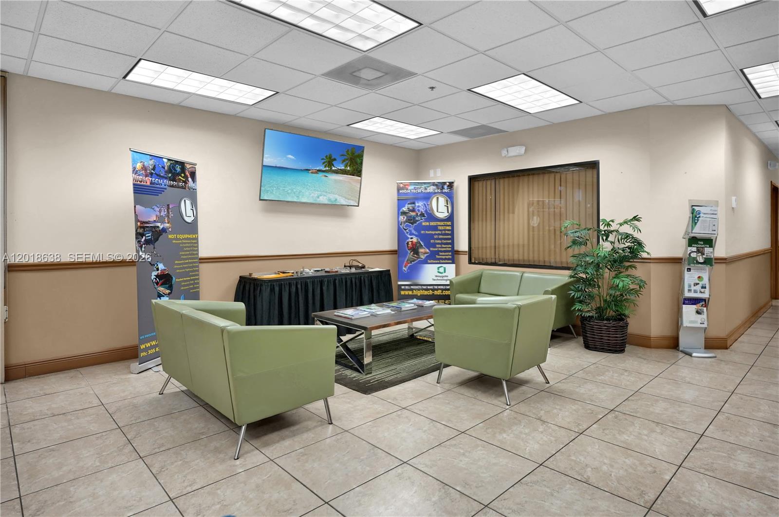 A waiting area with light green chairs, a coffee table, and branded display banners — 12601 NW 115th Ave # 114, Medley FL 33178, MEDLEY, FL
