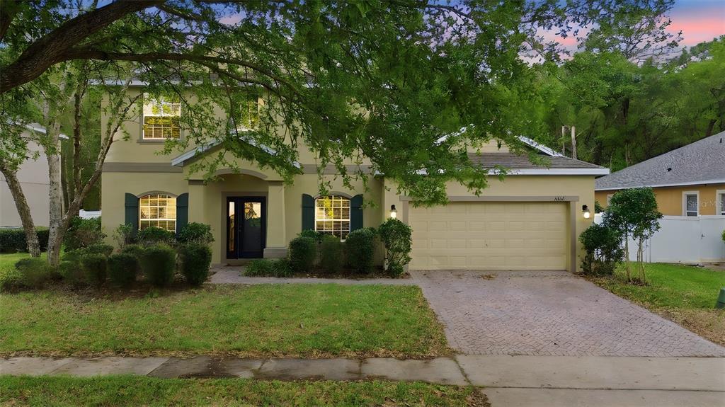 A two-story house with a beige exterior, a two-car garage, and a paved driveway — 1604 BLUE GRASS BOULEVARD, DELAND, FL