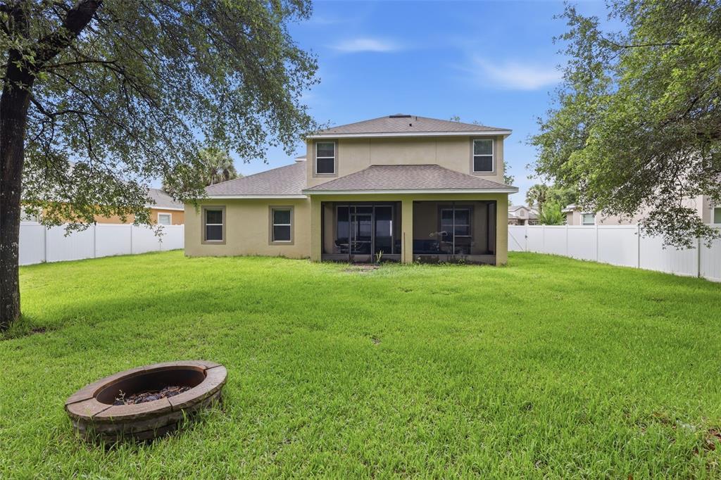 The backyard of a two-story house features a screened-in patio and a stone fire pit — 1604 BLUE GRASS BOULEVARD, DELAND, FL