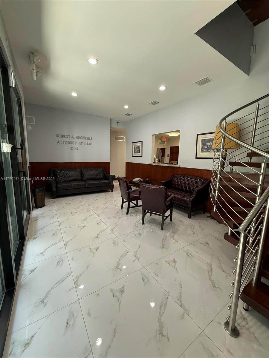 A waiting room features marble-look tile flooring, a spiral staircase, and dark leather seating — 16 SW 1st Ave, Miami FL 33130, MIAMI, FL