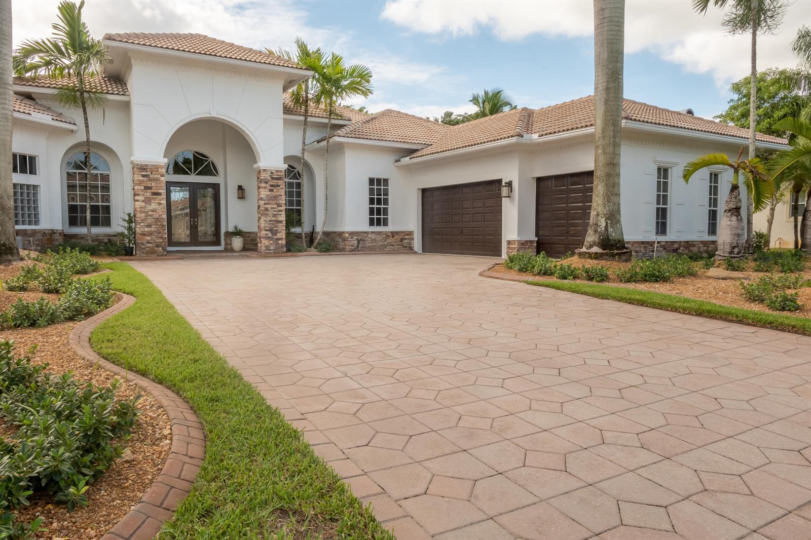 A single-story house with a paved driveway, stone accents, and a three-car garage — 12486 Equine Lane, Wellington FL 33414, WELLINGTON, FL